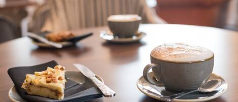 Una mesa con una porción de pastel, una taza de café y una cuchara.