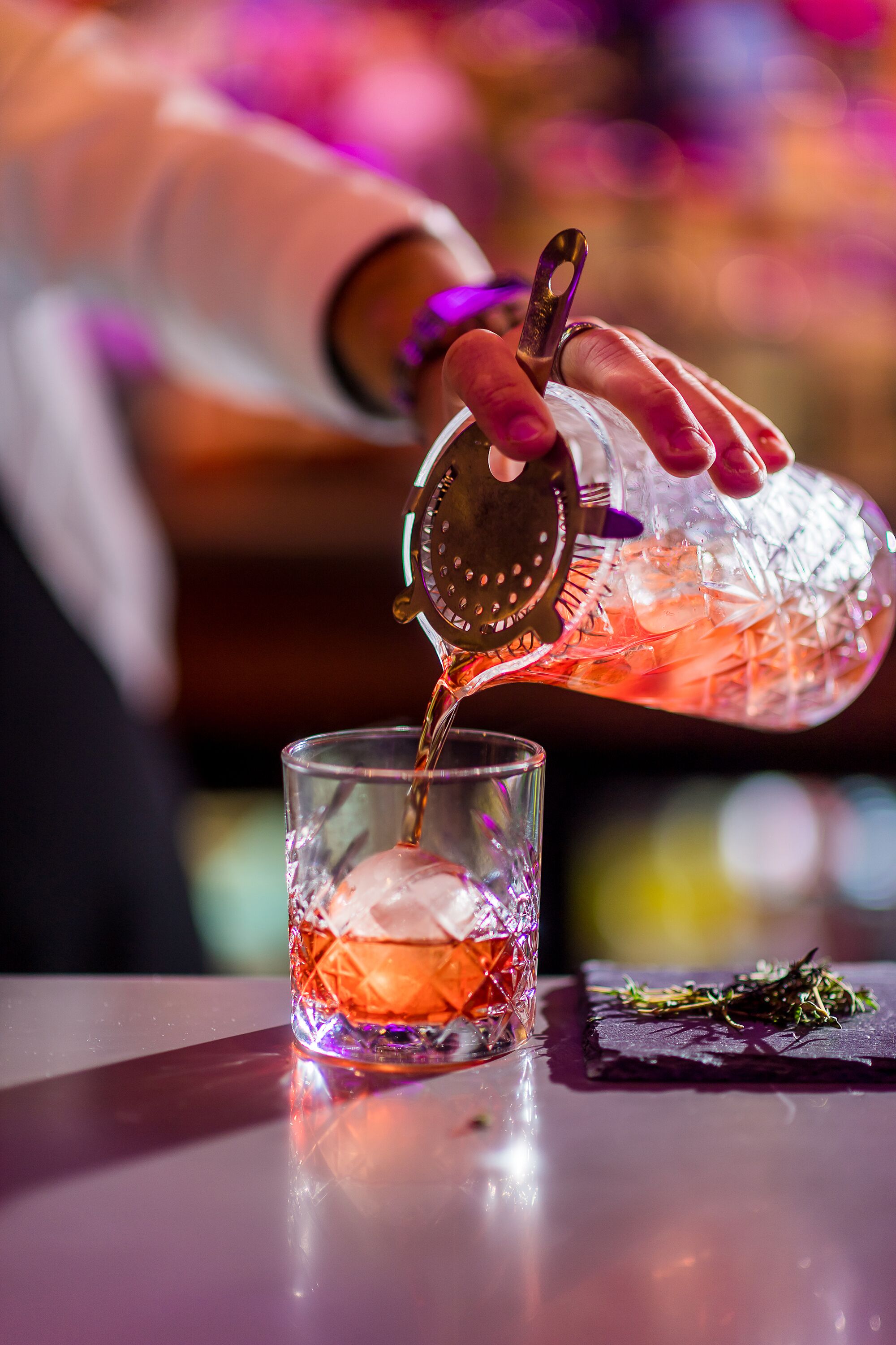 A bartender pouring a drink into a glass.