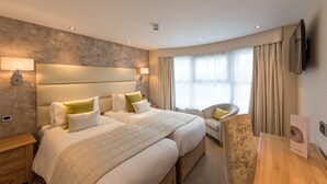 A hotel room with two beds, a sofa, a TV, and a desk. - The Royal & Fortescue (Barnstaple)