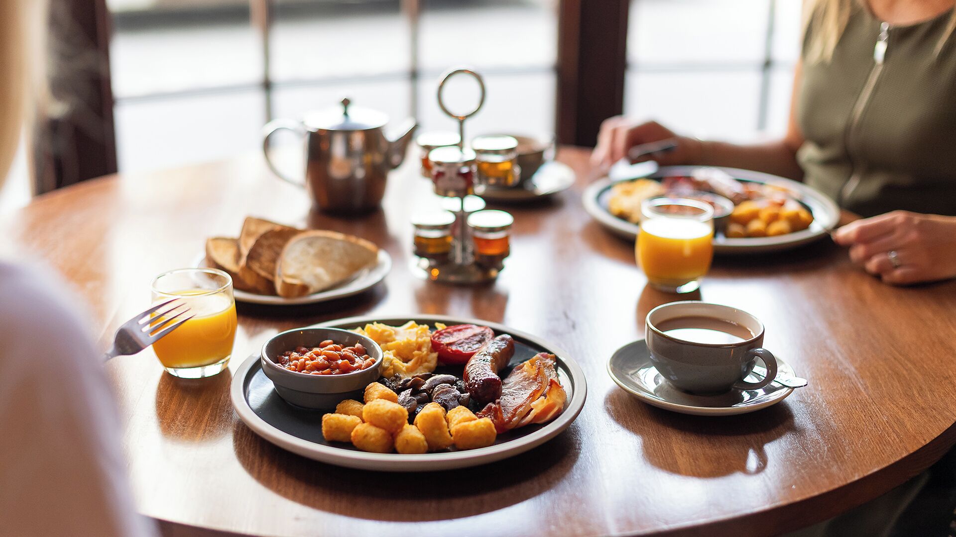 Un desayuno con platos de comida, una taza de café y un vaso de jugo de naranja.