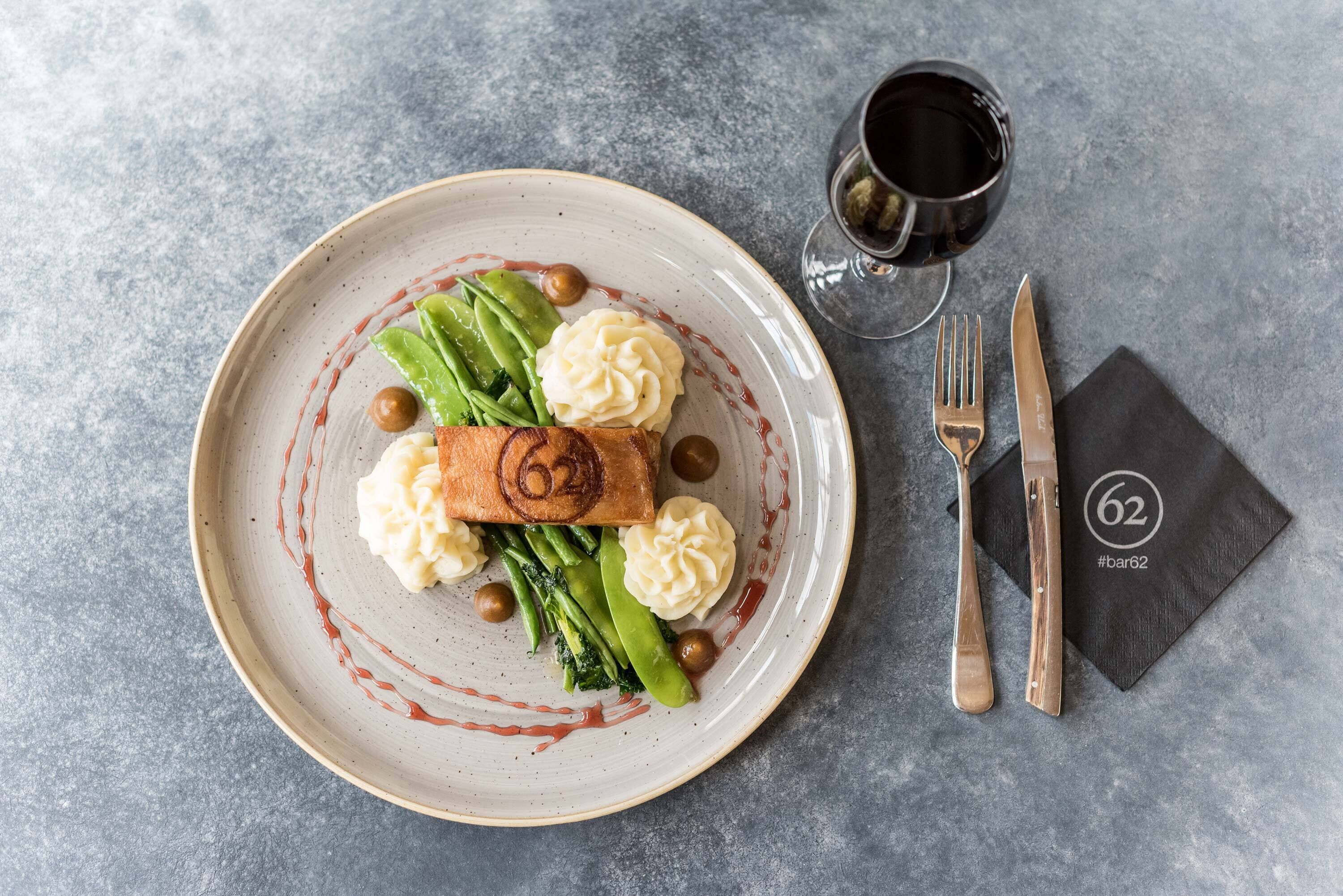 Une assiette remplie de nourriture, un verre contenant une boisson rouge et des couverts posés sur une surface texturée.