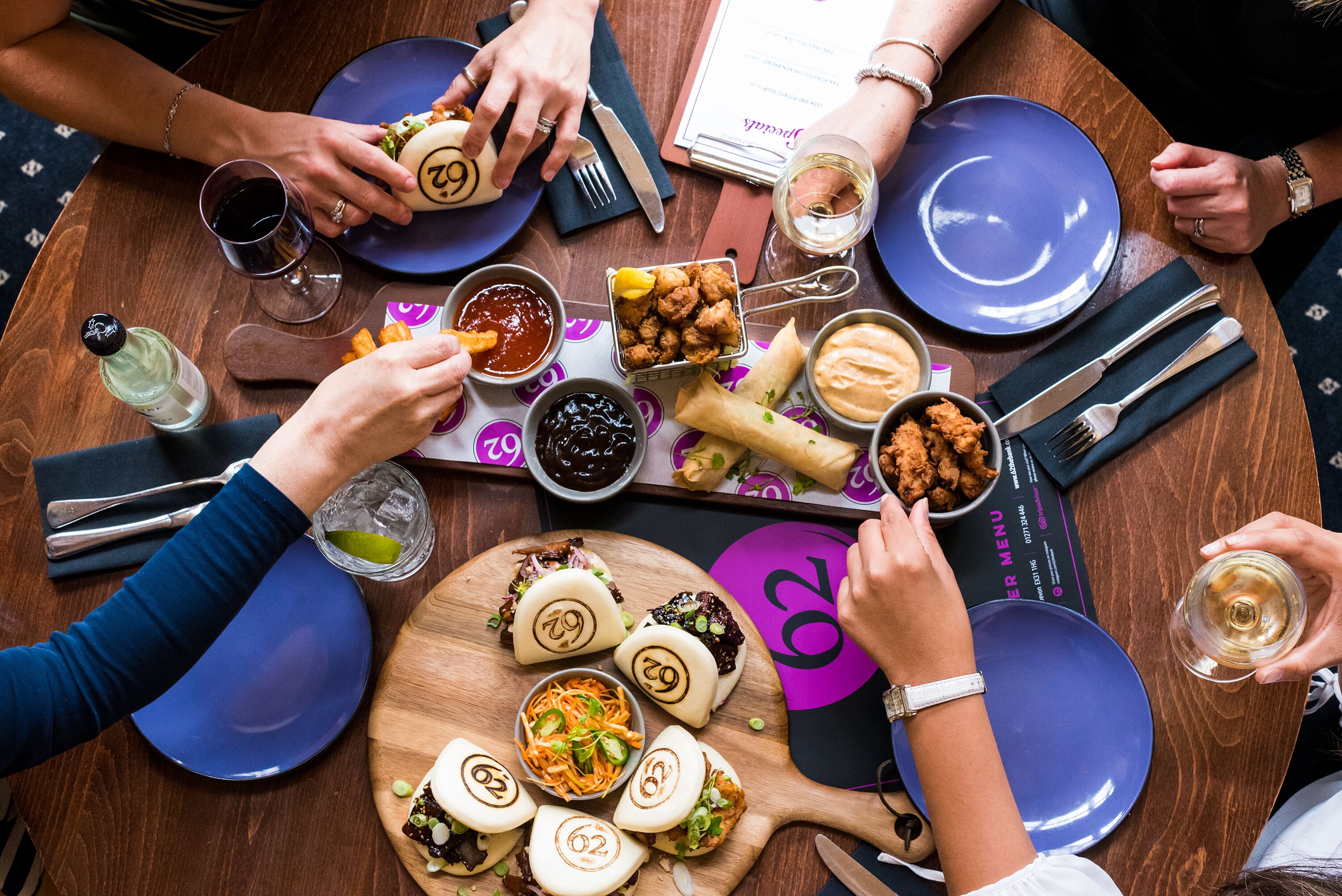 A group of people dining at a table with various dishes and drinks.