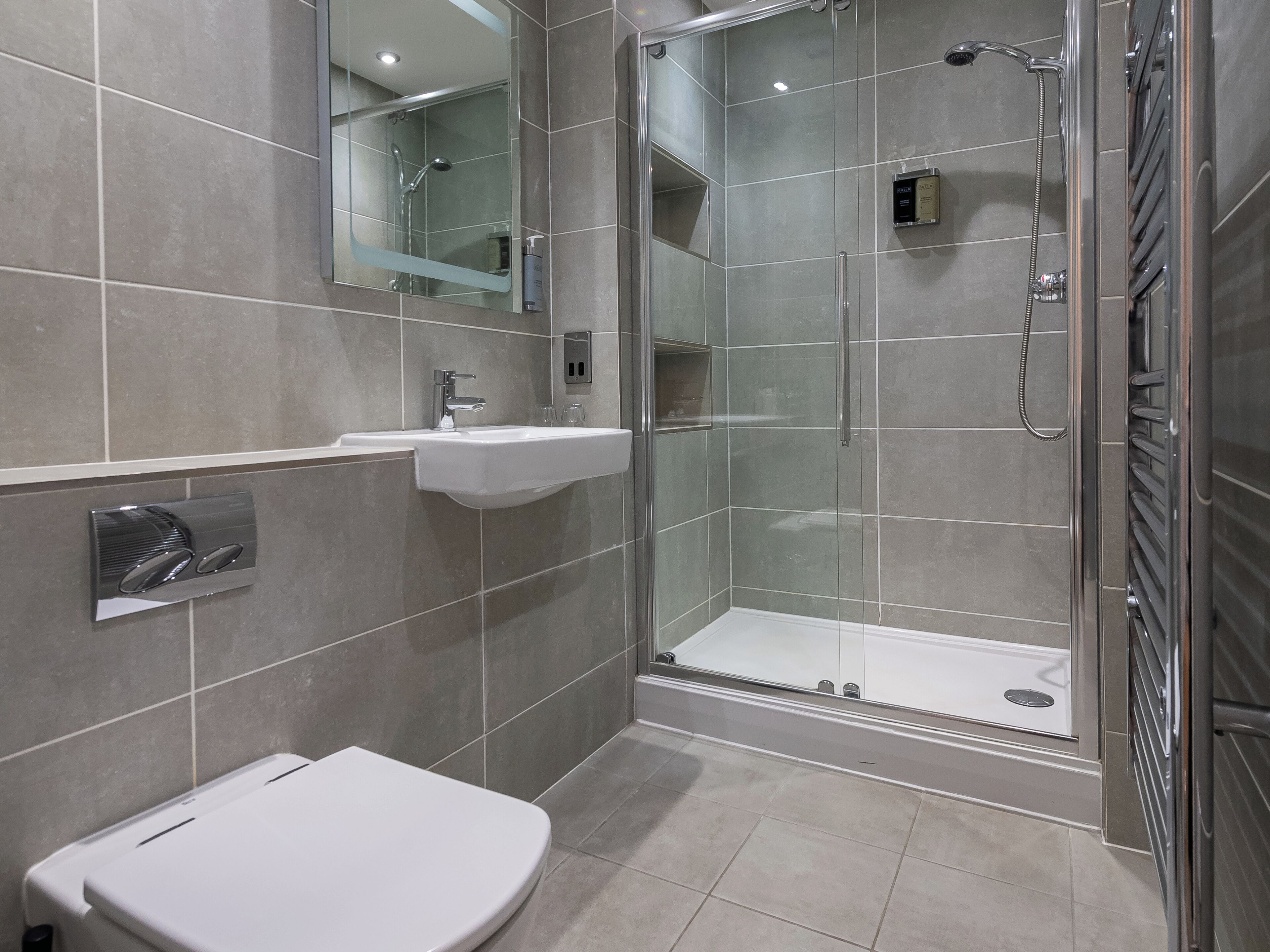 Un baño moderno con ducha de vidrio, lavamanos blanco y un inodoro.