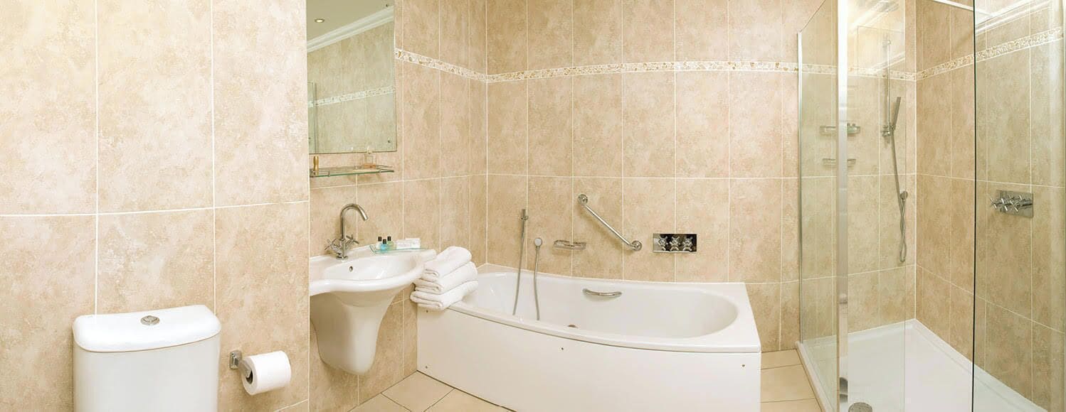 A bathroom with a bathtub, a sink, and a glass shower enclosure.