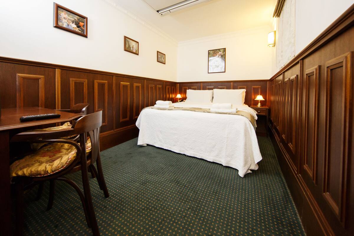 A hotel room with a bed, a desk, a chair, and a television.