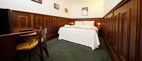 A hotel room with a bed, a desk, a chair, and a television.