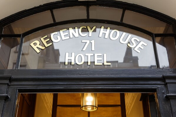 A hotel sign with the name "REGENCY HOUSE 71 HOTEL" in a classic arched window design.