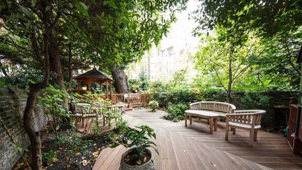 A wooden deck with a gazebo, seating area, and potted plants. - Regency House (London)