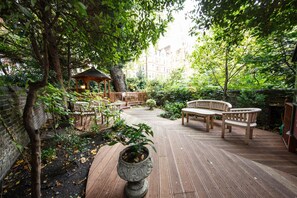 A wooden deck with a gazebo, seating area, and potted plants.