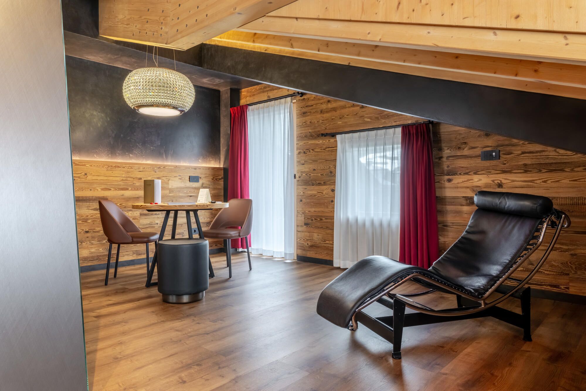 A modern interior with a wooden ceiling, a dining area with chairs and a table, and a leather chair.