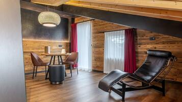 A modern interior with a wooden ceiling, a dining area with chairs and a table, and a leather chair.