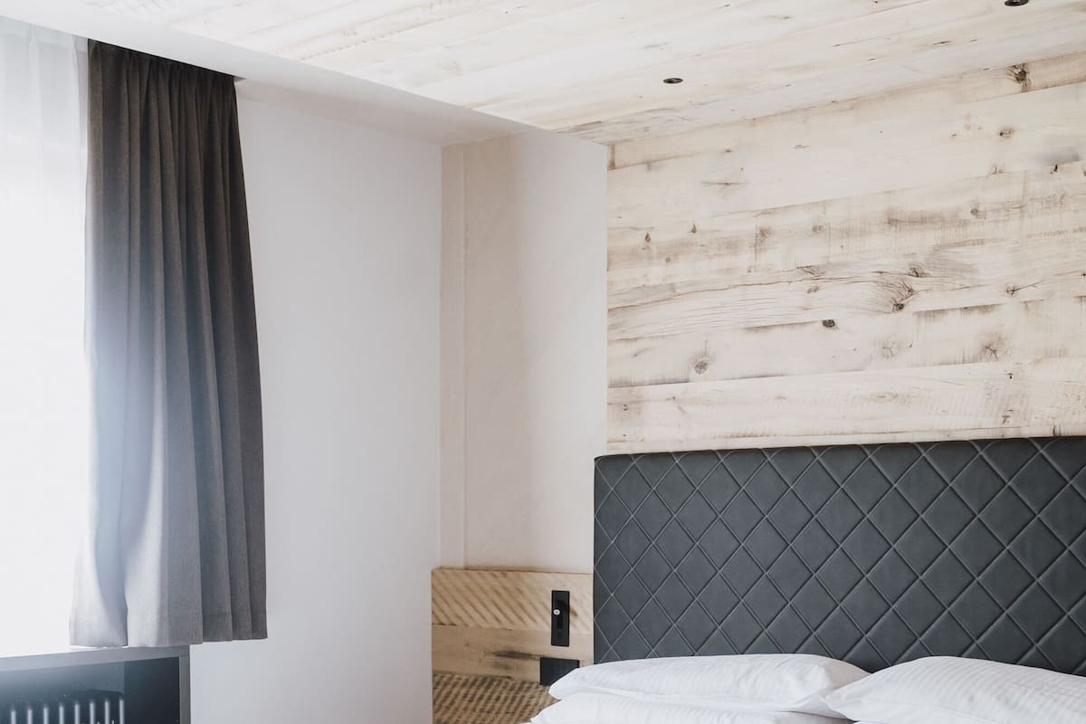 Una cama bien hecha en una habitación con techo de madera y cabecera.
