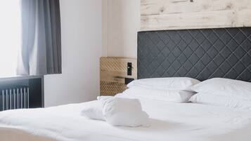 Un lit bien fait dans une pièce dont le plafond est en bois et qui est agrémenté d’une tête de lit.