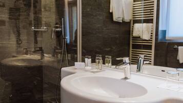 Un baño moderno con un lavamanos grande de color blanco, una mampara de ducha de vidrio y un perchero para toallas.