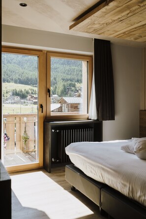 Un dormitorio con cama, ventana con vista a un bosque y techo de madera.