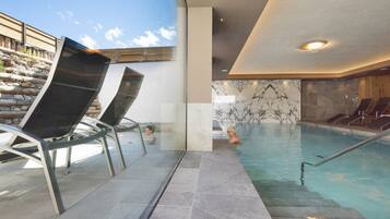Relax by the pool with a clear view of the sky, surrounded by lounge chairs and a decorative marble wall.
