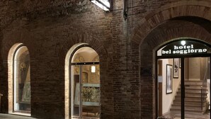 Entrada de un hotel con arquitectura de ladrillo y arcos, y un cartel que dice "hotel bel soggiorno".