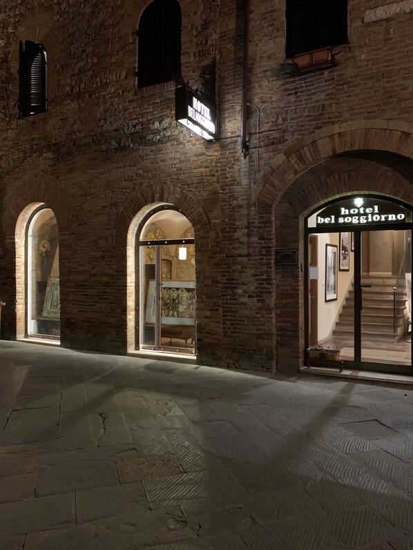 A hotel entrance with arched brick architecture and a sign reading "hotel bel soggiorno".