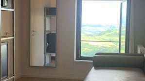 Una habitación moderna con un ventanal grande, una cama, un escritorio y un armario.