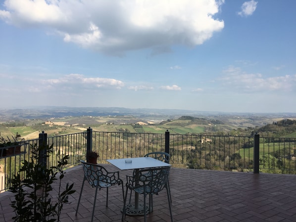 A terrace with a table and chairs, overlooking a scenic landscape.