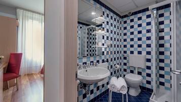 Un bany amb un dibuix de rajoles blava i blanca a quadres, un lavabo blanc, un vàter i una dutxa.