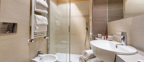 A modern bathroom with a glass-enclosed shower, a white sink, and a bidet.