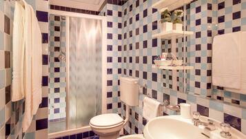Un baño con suelo de baldosas a cuadros, un inodoro, un lavamanos y una ducha.