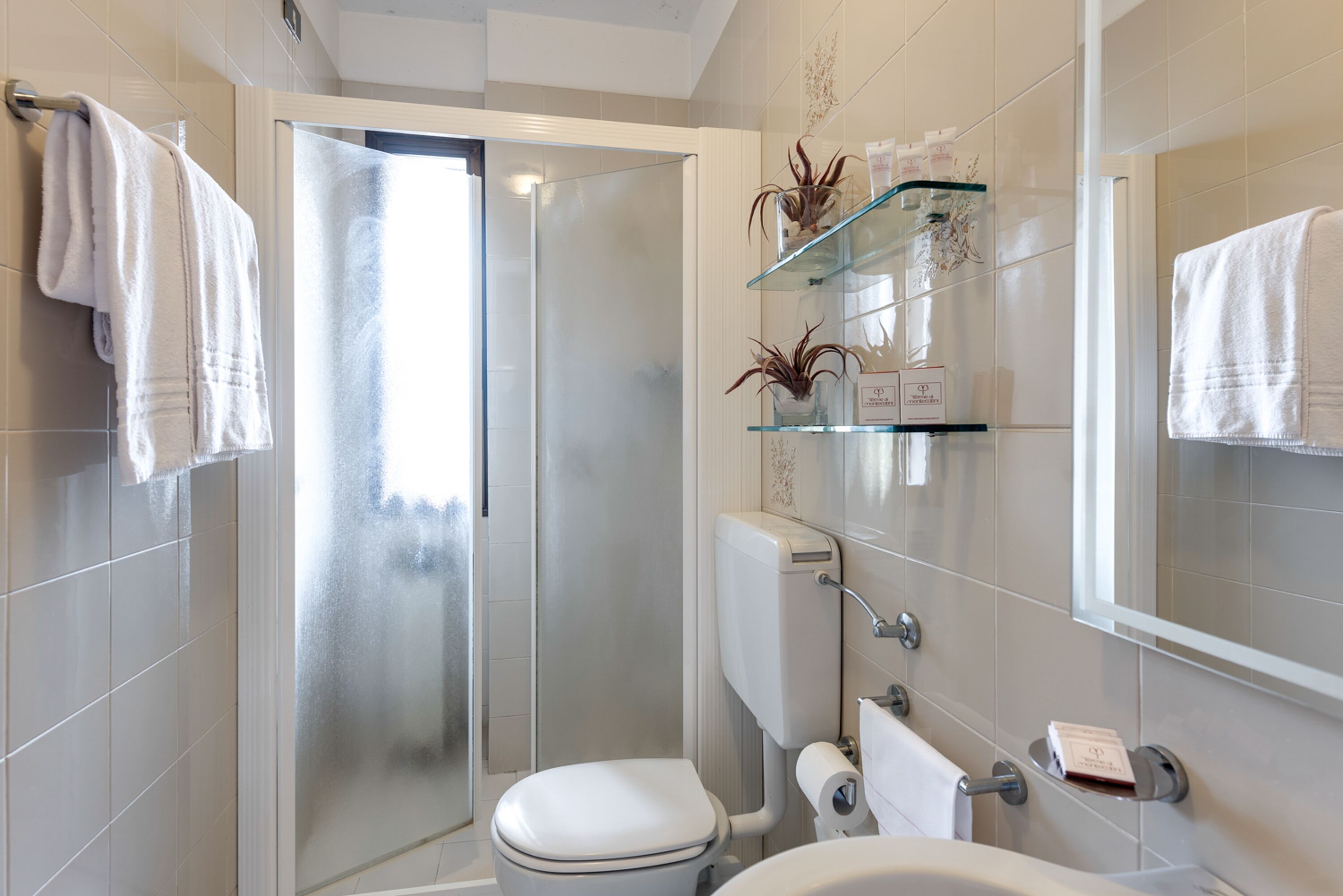 Ein modernes Badezimmer mit Duschkabine aus Glas, Toilette, Waschbecken und Spiegel.