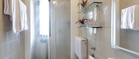 Ein modernes Badezimmer mit Duschkabine aus Glas, Toilette, Waschbecken und Spiegel.