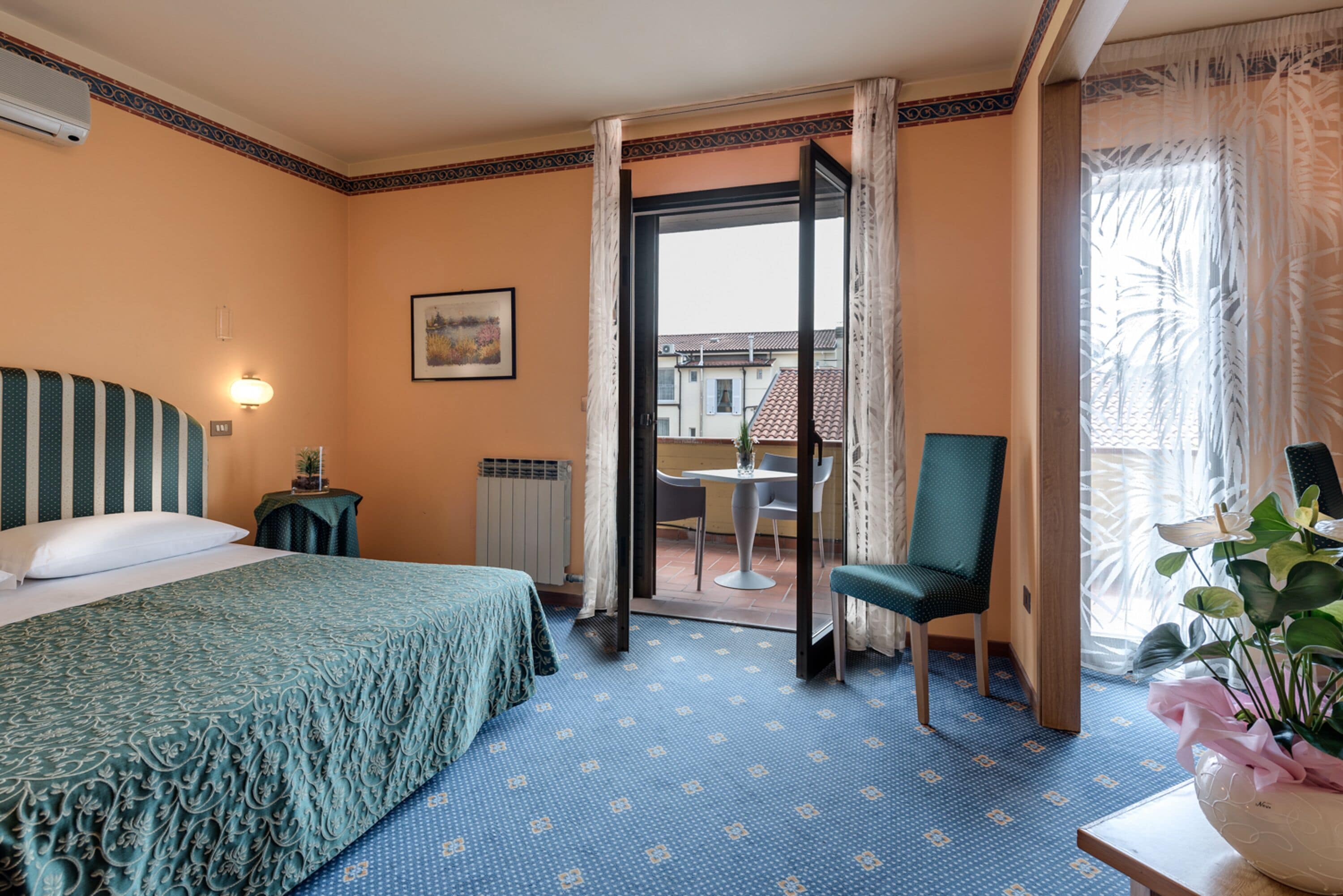 Ein Hotelzimmer mit einem Bett, einem Sessel, einem Tisch und Blick ins Freie.