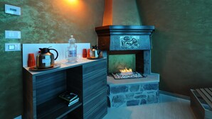 Eine moderne Küche mit Kamin aus Stein, einer Kaffeemaschine und einem Wasserkocher auf der Arbeitsfläche.