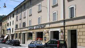 Ein Hotel namens "HOTEL BERTUSI" mit mehreren parkenden Autos davor.