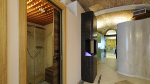 Ein modernes Badezimmer mit Glasdusche, einer Holzbank und einem vertikalen, schwarzen Gestaltungselement.