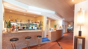 Una zona de bar con taburetes, estanterías llenas de botellas y una barra.