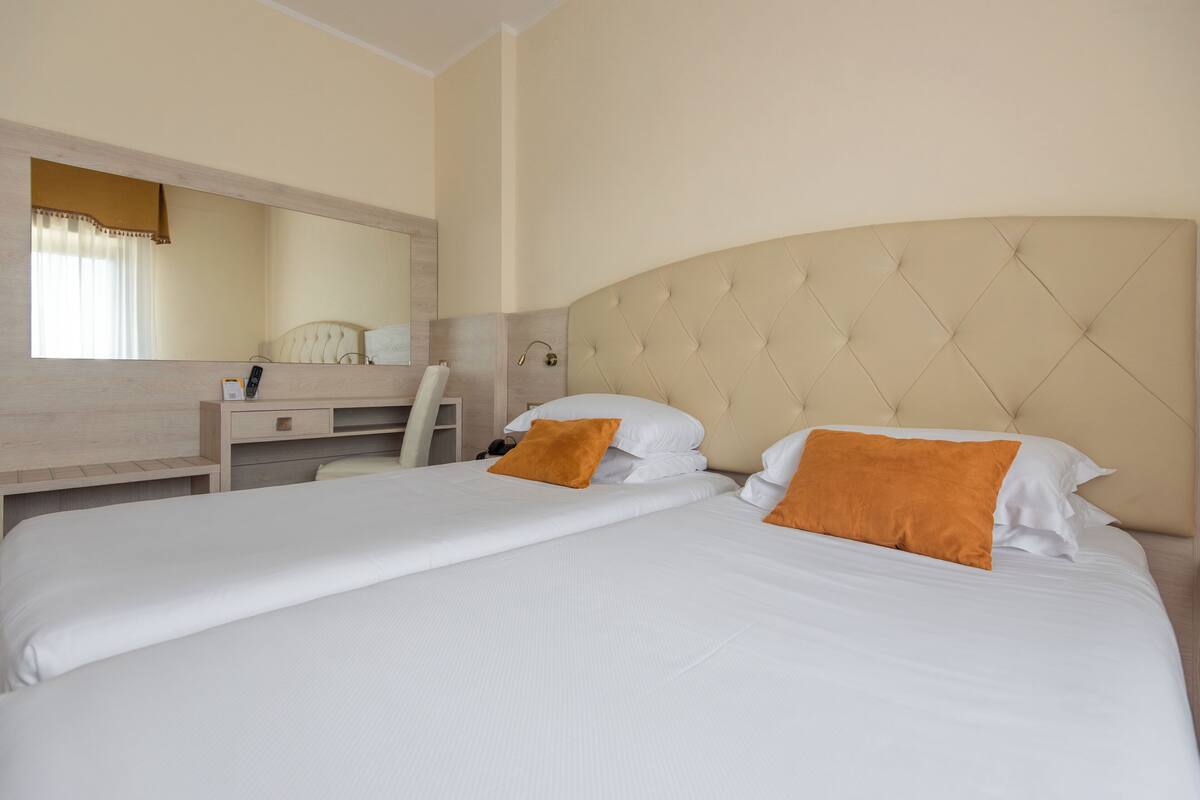 A hotel room with a large bed, a desk, and a chair.