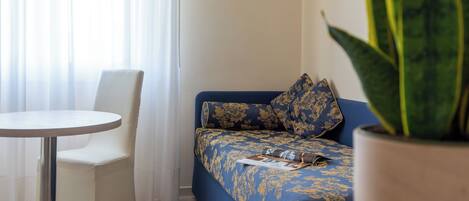 A room with a blue sofa, white chair, and a round table.