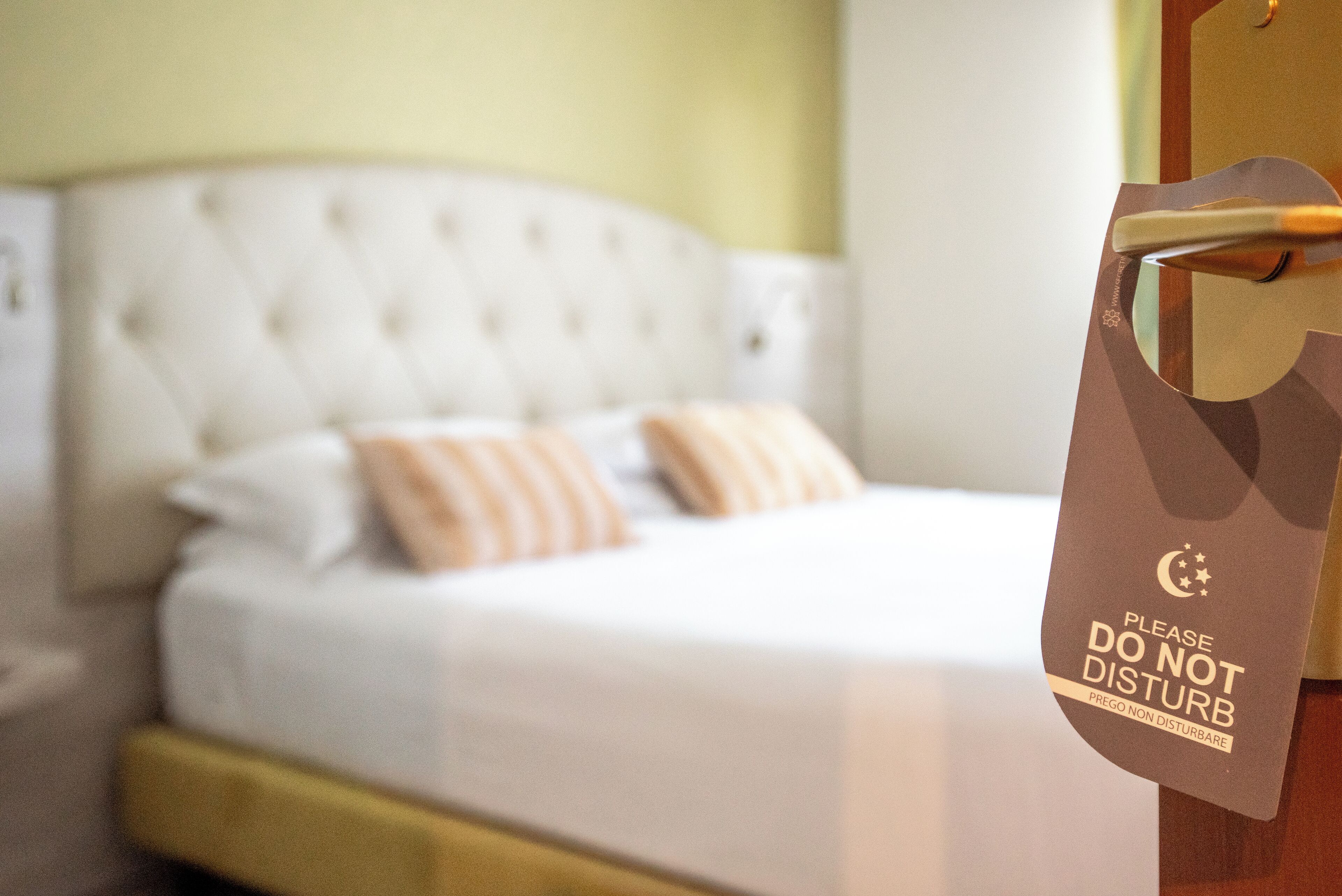 Ein Hotelzimmer mit einem Bett, einem Schild an der Tür und einer Wand mit Lichtschalter.