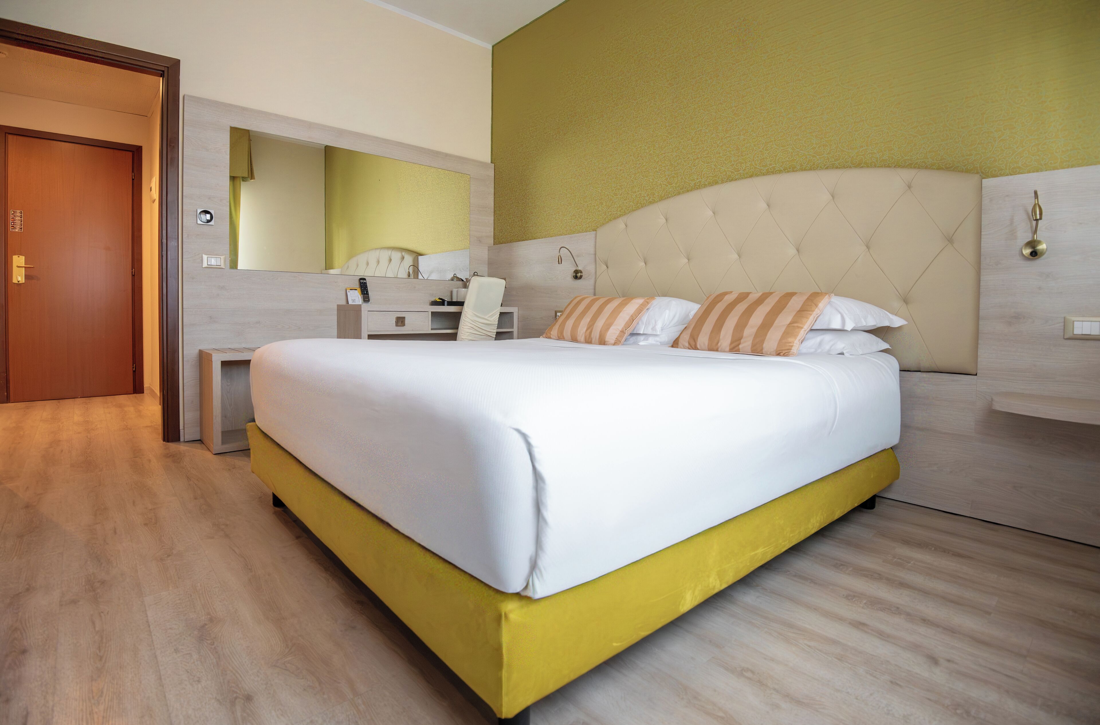 Une chambre d’hôtel moderne, dotée d’un grand lit, d’un bureau et d’un miroir.