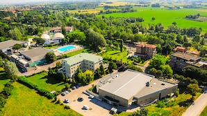 Vista aérea de un hotel con un edificio grande, una piscina y campos verdes circundantes.