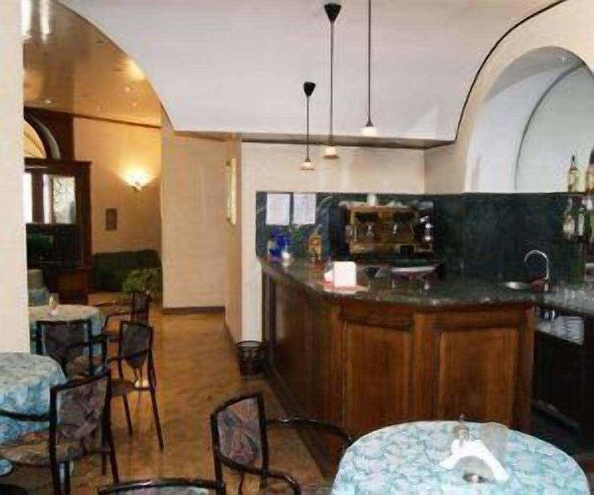 Zona de bar con mostrador de madera, taburetes y una pequeña mesa redonda con un objeto decorativo.