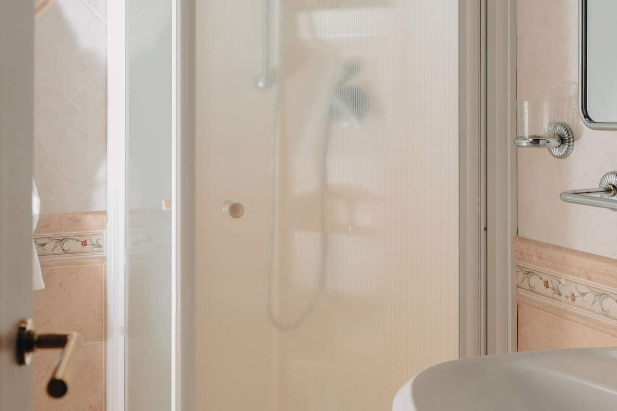 A bathroom with a glass-enclosed shower, a white sink, and a towel rack.
