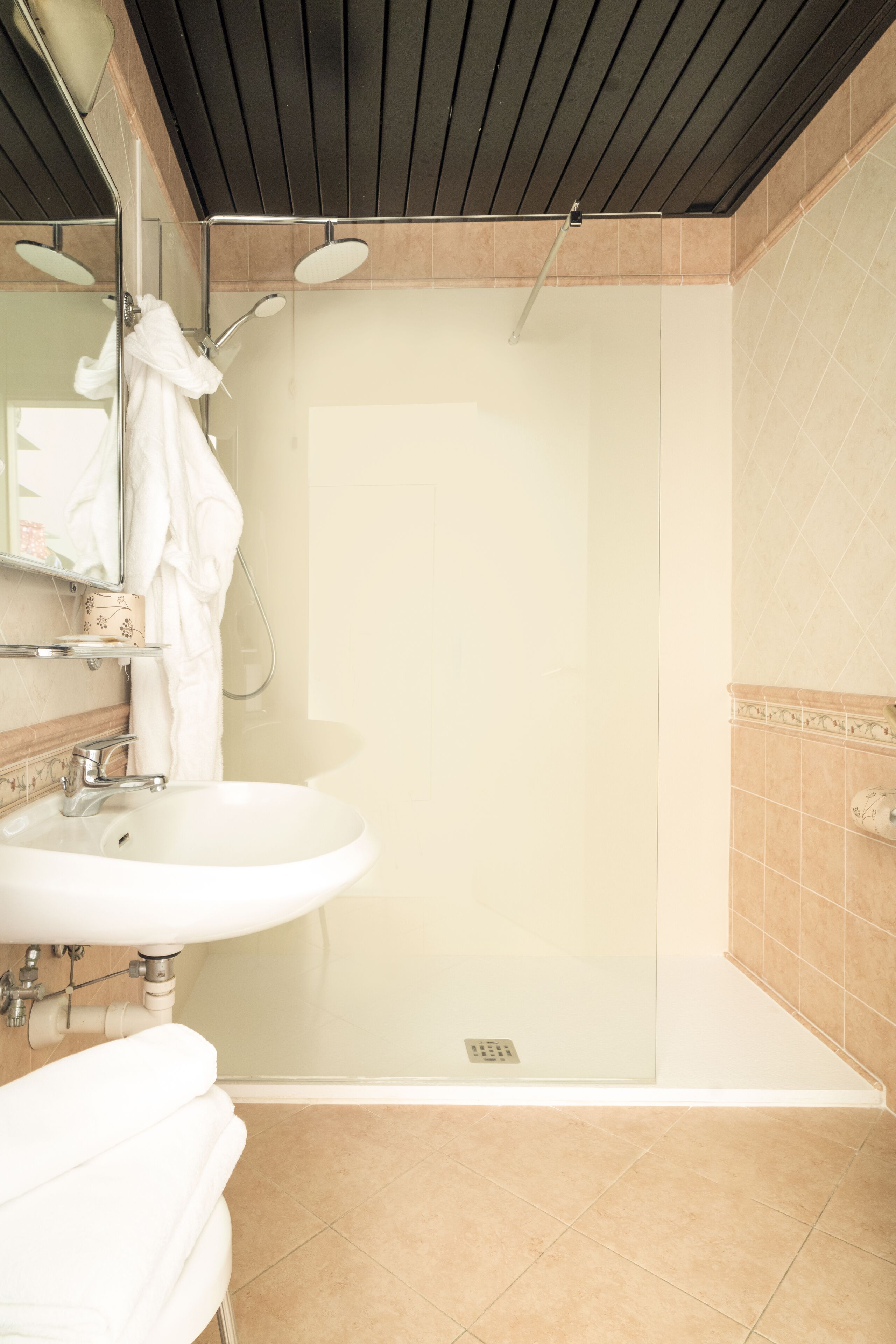 A modern bathroom with a glass-enclosed shower, a white sink, and a mirror.