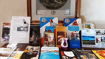 Un bureau avec des brochures, un tableau encadré et un verre à vin.