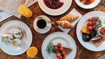 A breakfast table with various dishes including eggs, toast, tomatoes, and a croissant.