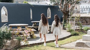 A courtyard with a wooden table and chairs, surrounded by greenery and a stone wall with arched windows. - The Royal Hotel (Bideford)