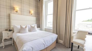 A neatly arranged bedroom with a large bed, bedside tables, and a chair.