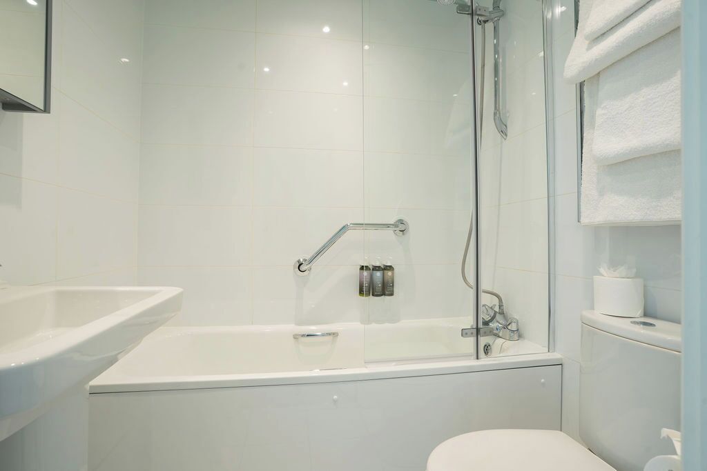 Un baño moderno con ducha de vidrio, una bañera blanca y un inodoro.