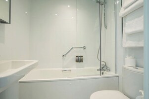 Un baño moderno con ducha de vidrio, una bañera blanca y un inodoro.