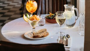 A dining table with a salad, bread, and drinks, set in a restaurant with a checkered floor and wooden chairs. - The Royal Hotel (Bideford)