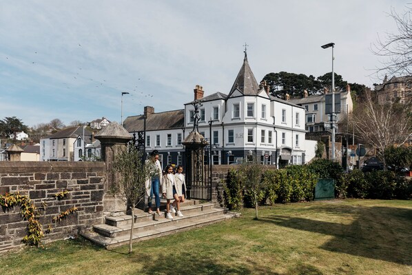 A historic building with a prominent tower, a stone wall, and a well-maintained lawn. - The Royal Hotel (Bideford)